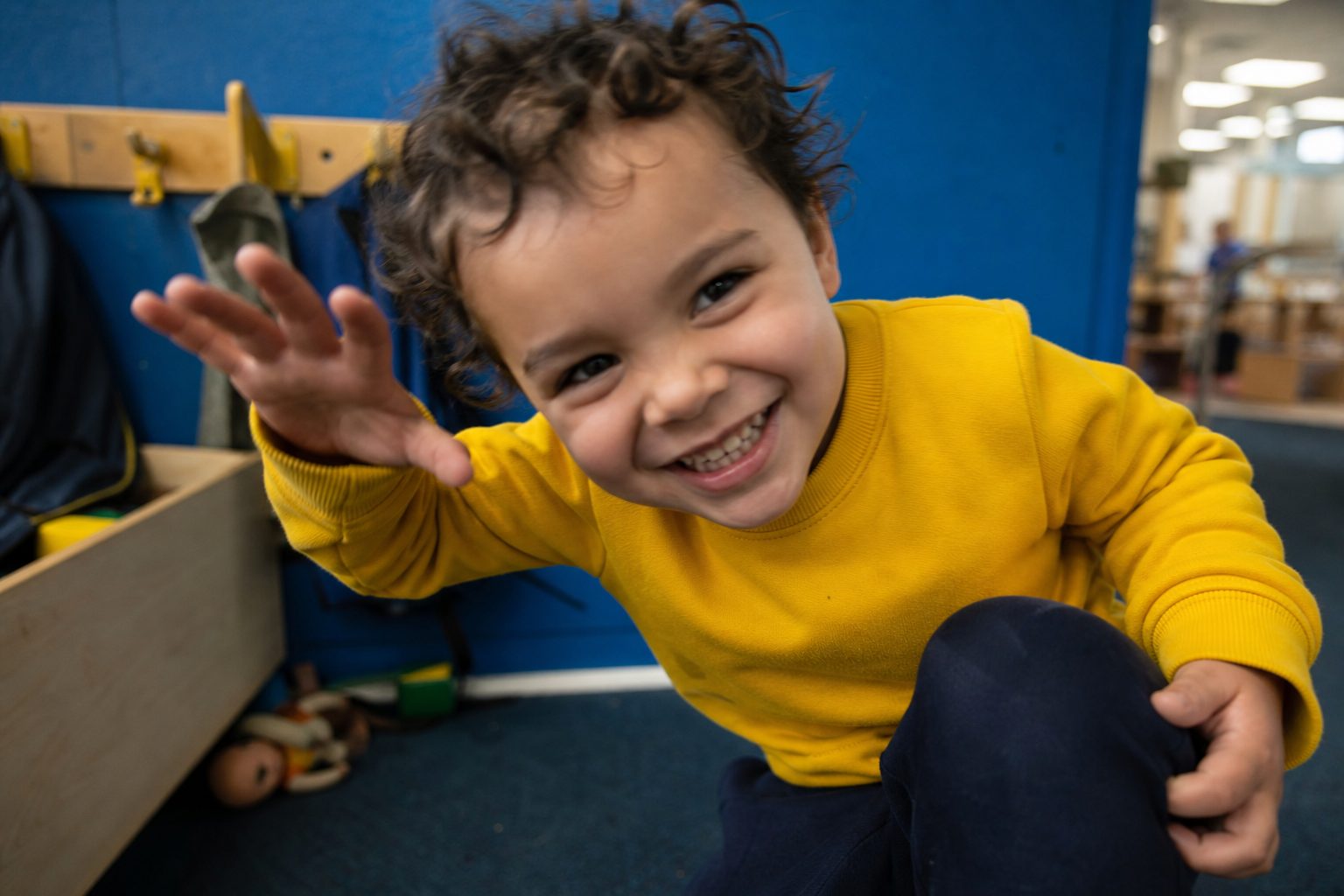 A grinning child pulling a cheeky face against a bright blue wall