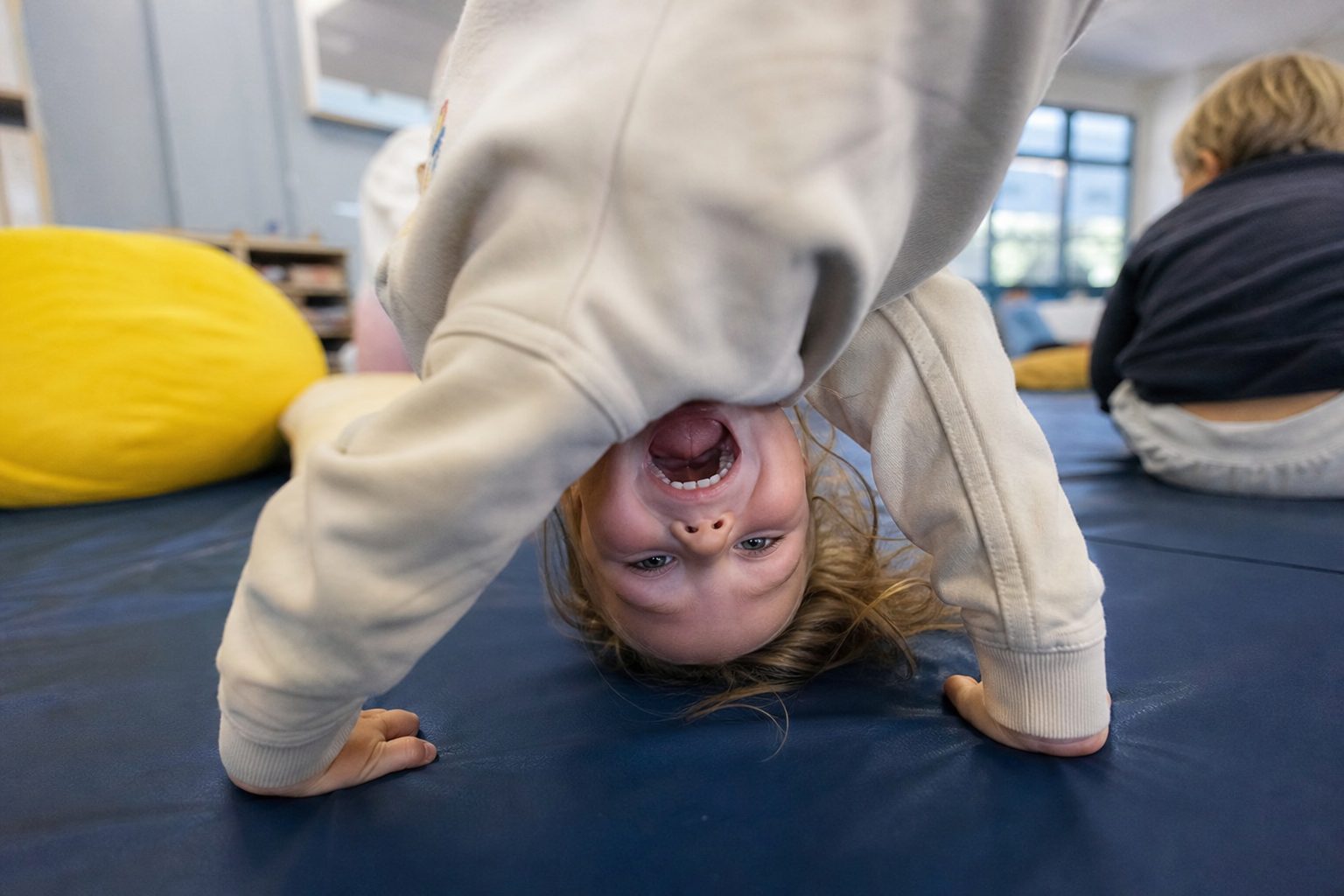 Child upside down laughing on a play mat