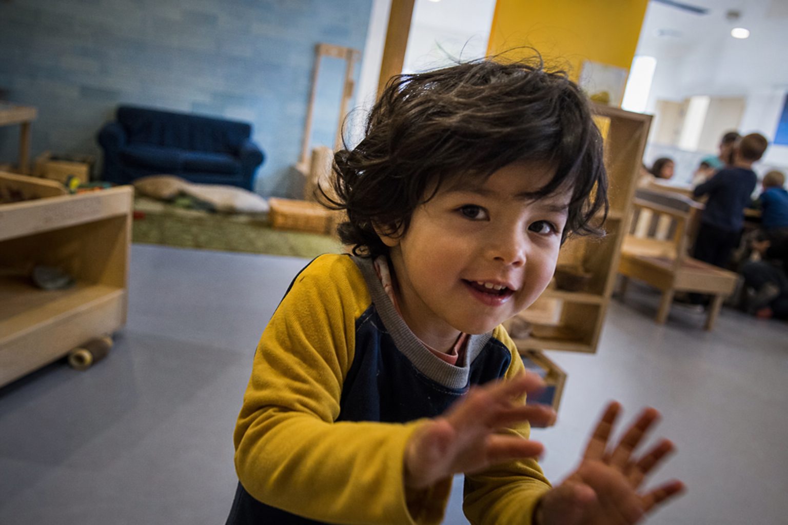 A shy child photographed gently, half smiling, in soft indoor light