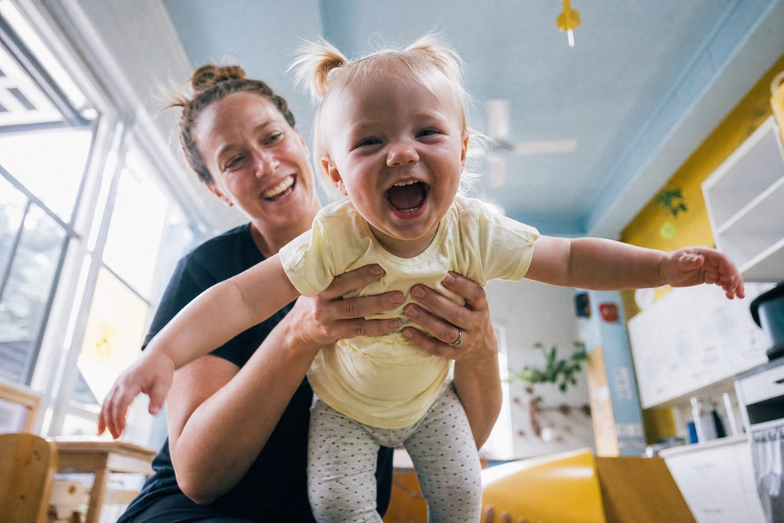 Educator holding a laughing baby up to the camera