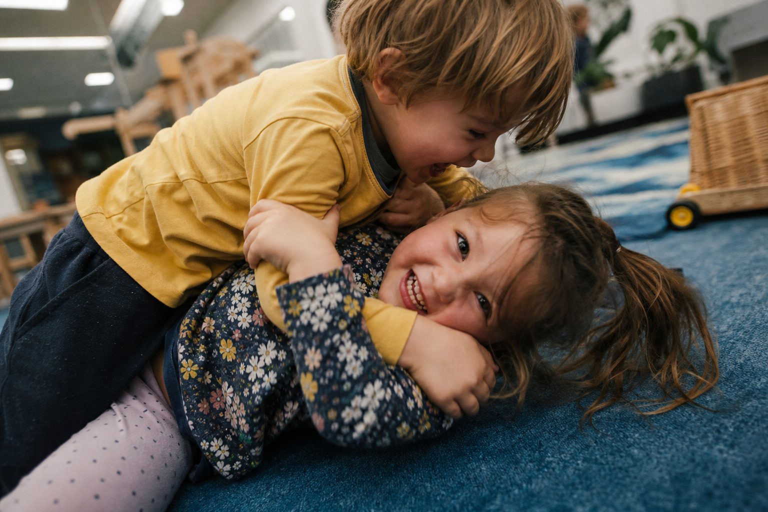 Two siblings wrestling and laughing together