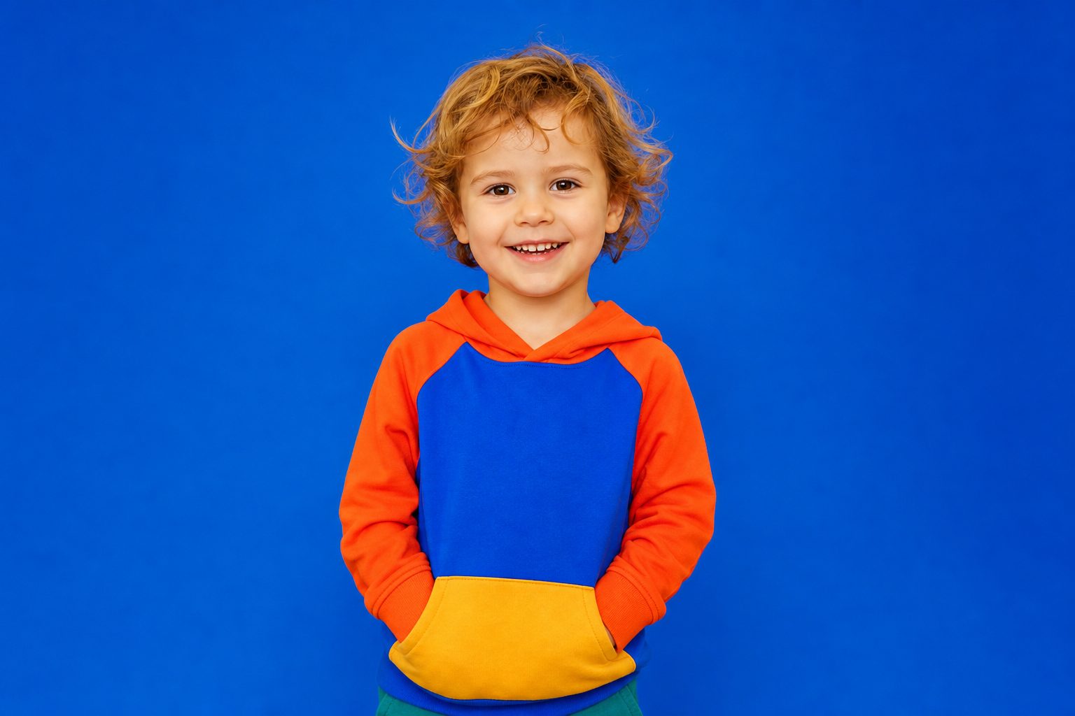 Child against an electric blue backdrop looking straight to camera