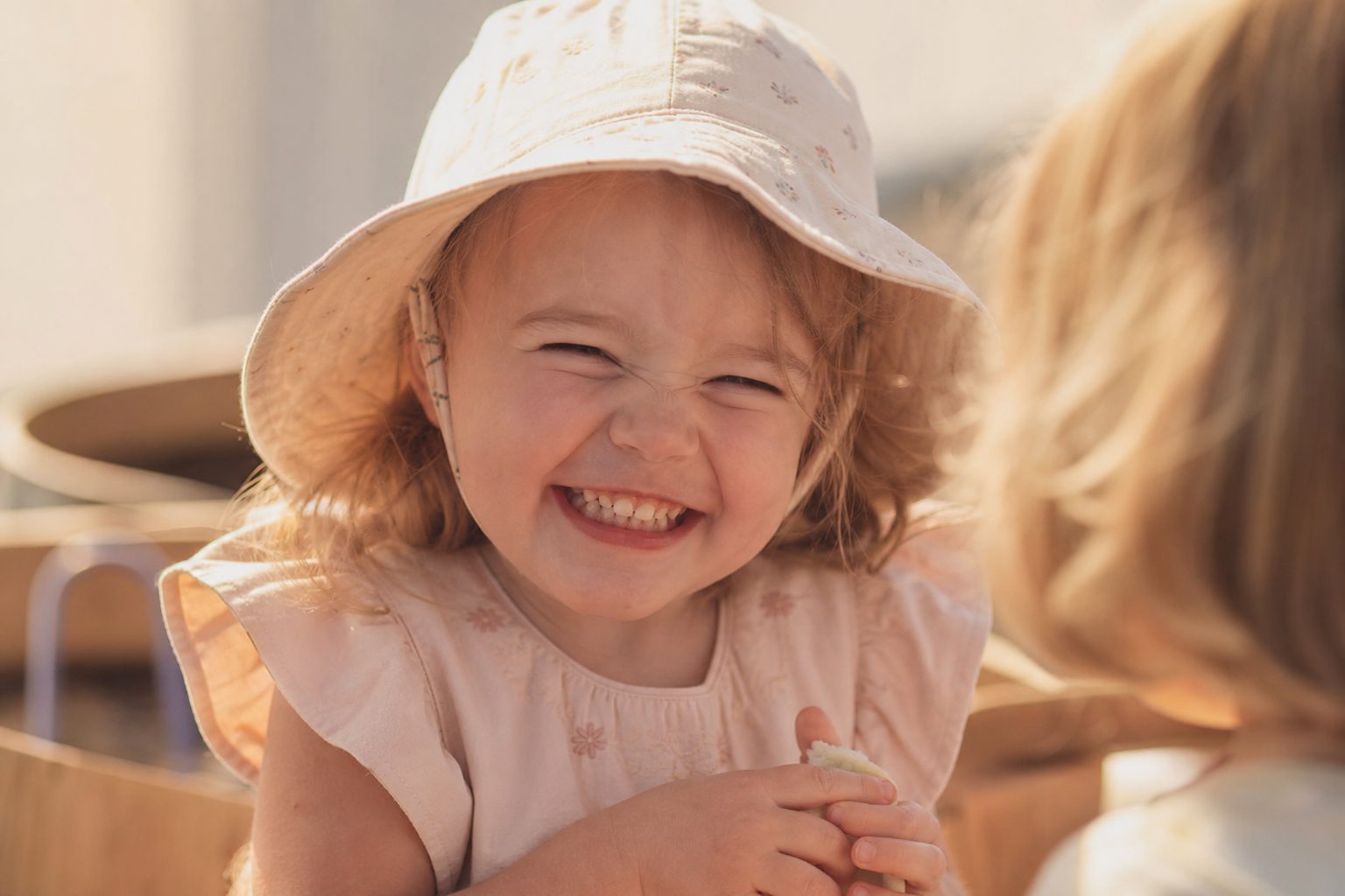 Small child in a sun hat squinting happily